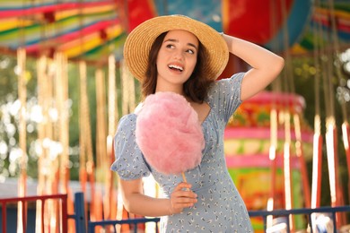 Photo of Beautiful young woman with cotton candy at funfair