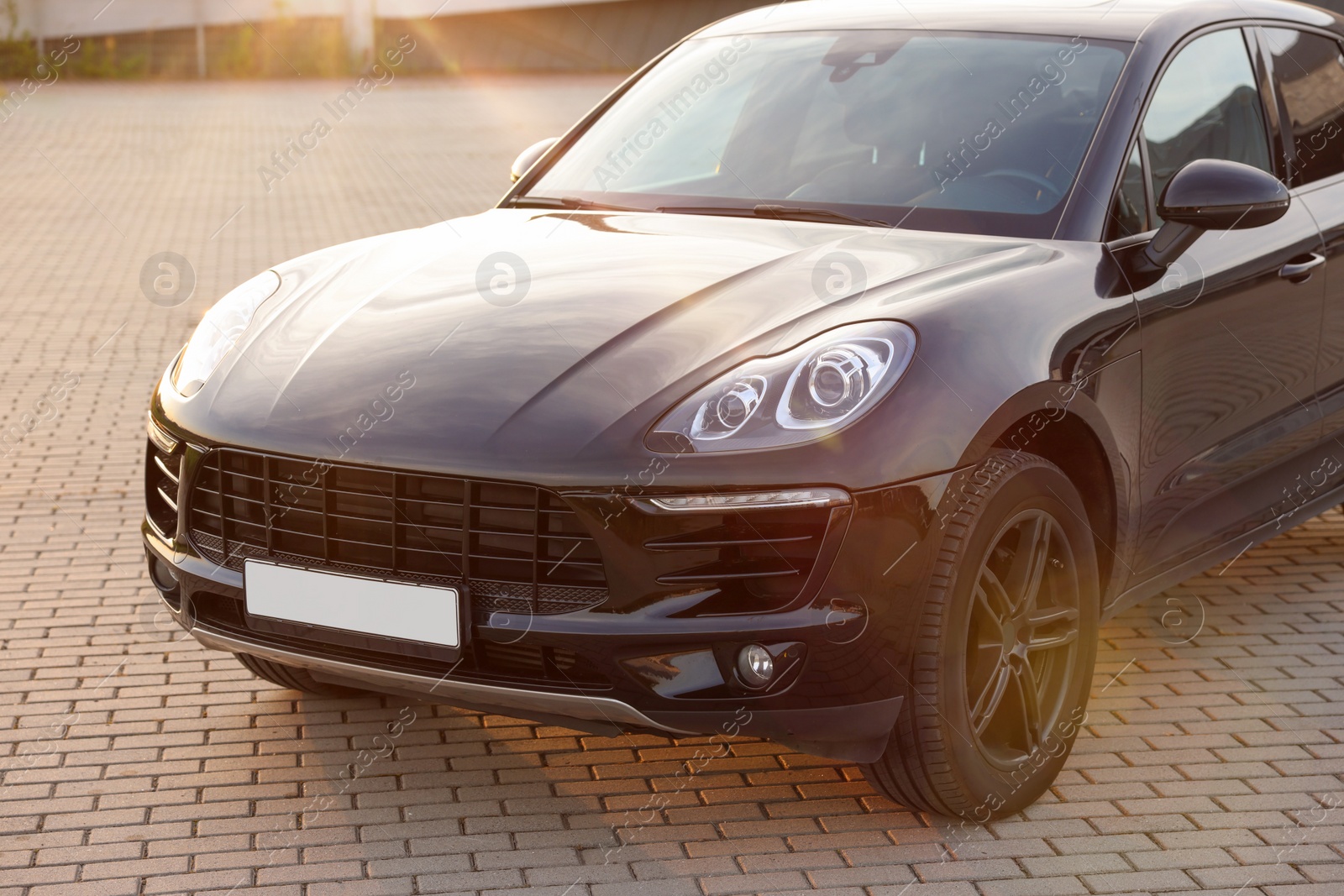 Photo of Modern black car parked on stone pavement outdoors