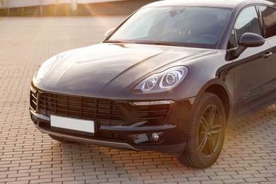 Photo of Modern black car parked on stone pavement outdoors