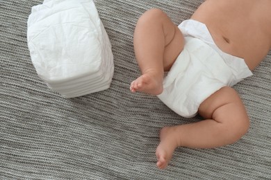 Photo of Cute little baby in diaper on grey blanket, top view