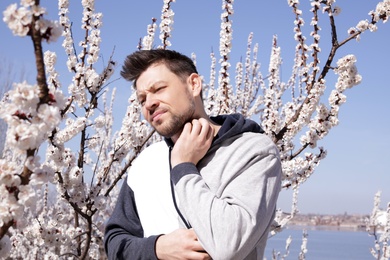Photo of Man suffering from seasonal allergy outdoors on sunny day