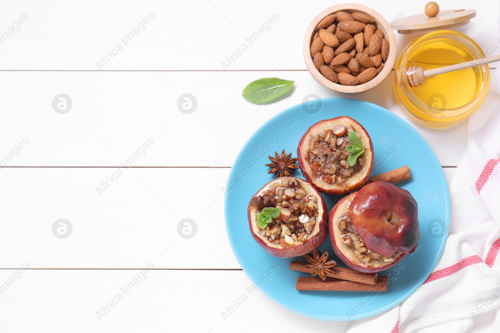 Photo of Tasty baked apples with nuts, honey, spices and mint on white wooden table, flat lay. Space for text