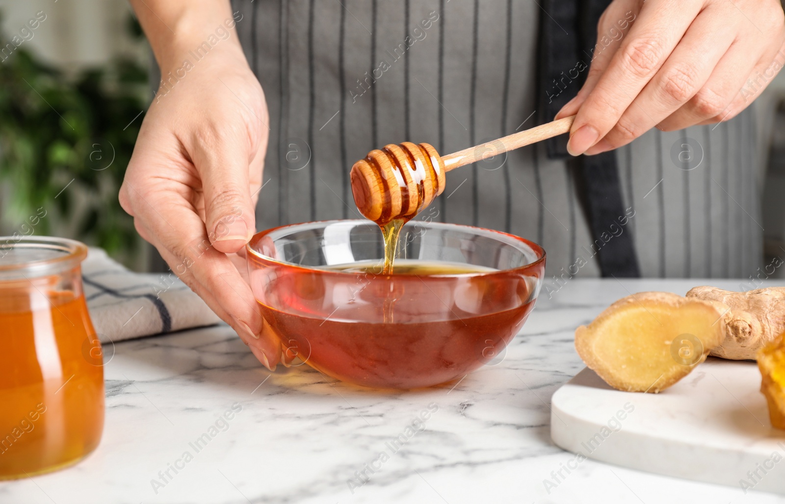 Photo of Woman with tasty honey at marble table, closeup