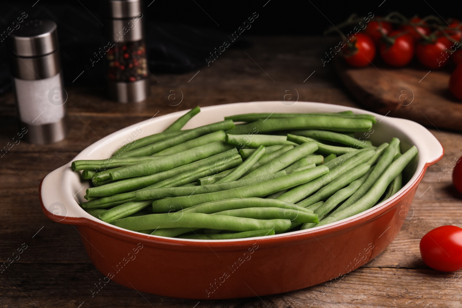 Photo of Raw green beans in baking dish on wooden table