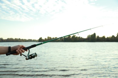 Photo of Fisherman with rod fishing at riverside, closeup