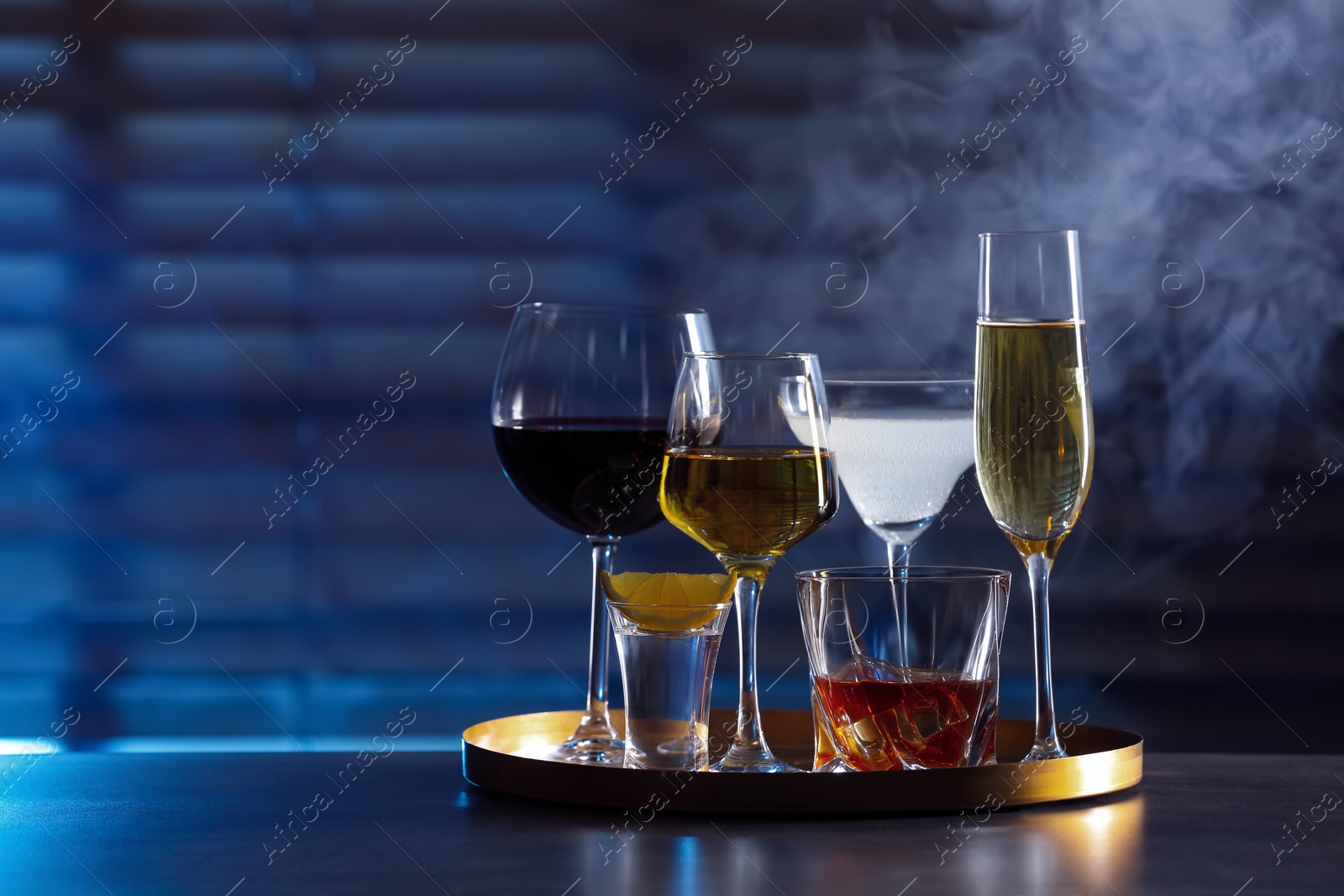 Photo of Tray with different alcohol drinks on table indoors