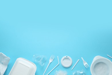 Photo of Plastic dishware on light blue background, flat lay. Space for text