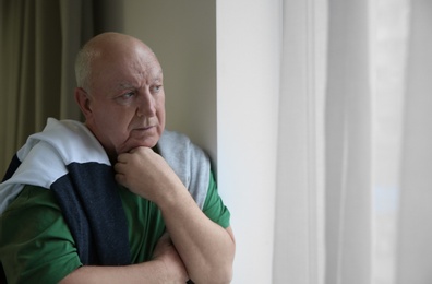 Photo of Portrait of elderly man near window indoors. Space for text