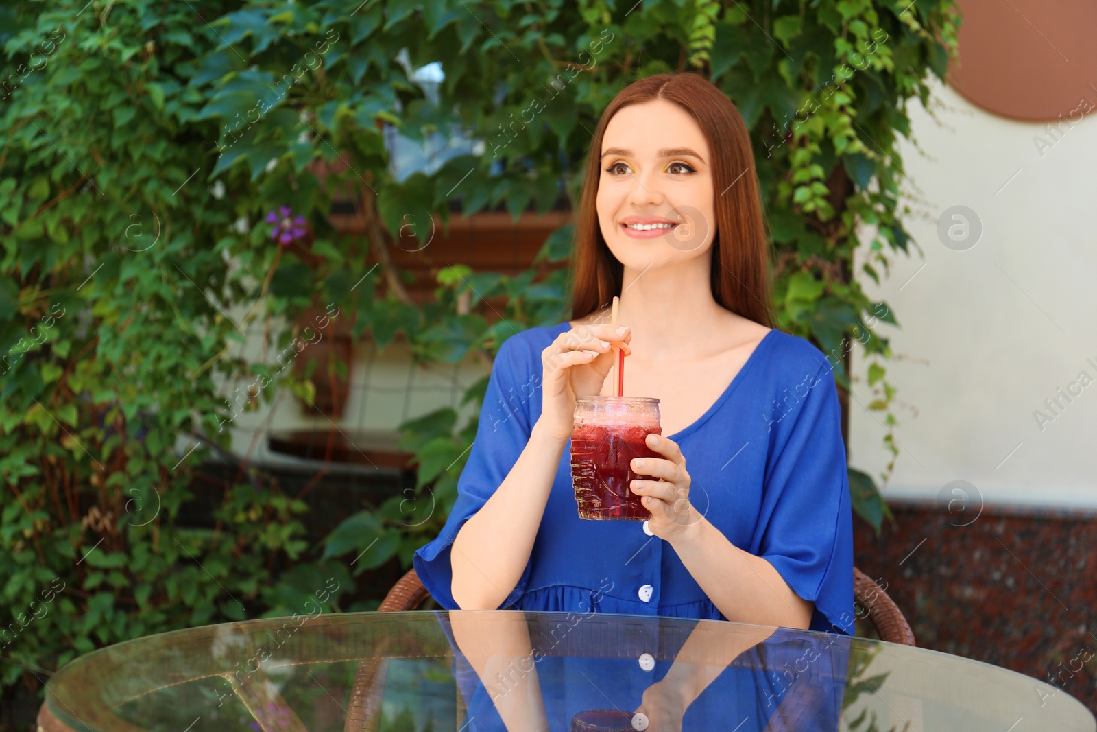 Photo of Beautiful young woman with glass of natural detox lemonade at table in outdoor cafe. Space for text