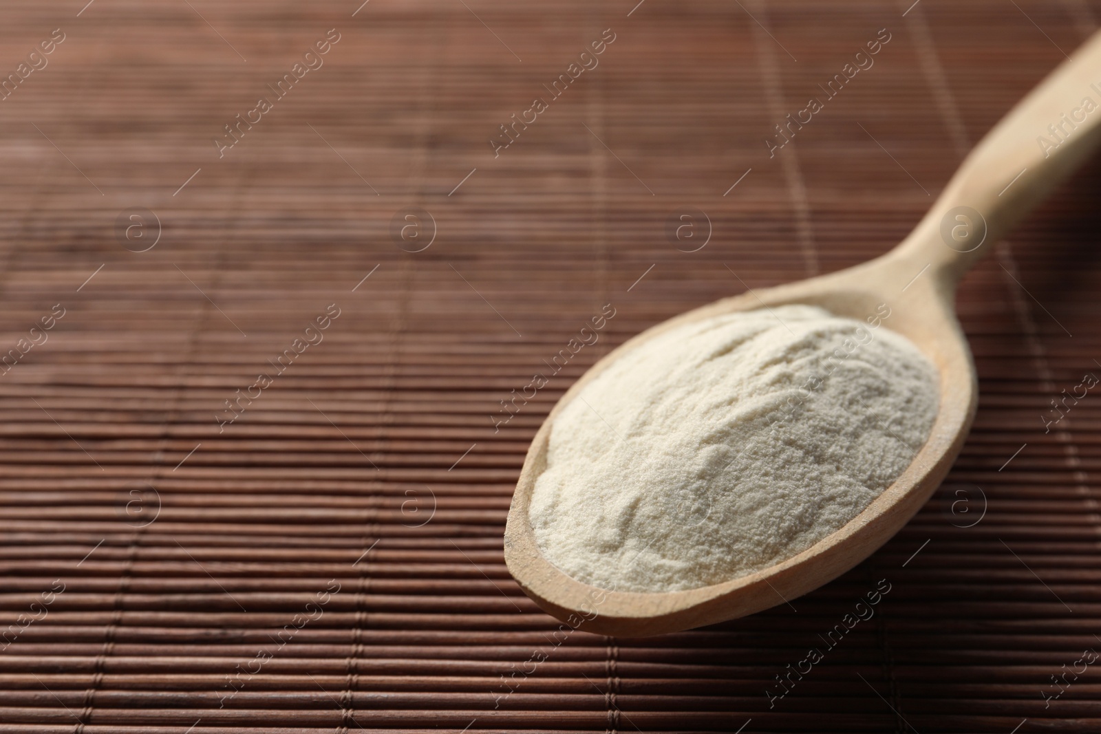 Photo of Spoon of agar-agar powder on bamboo mat, closeup. Space for text