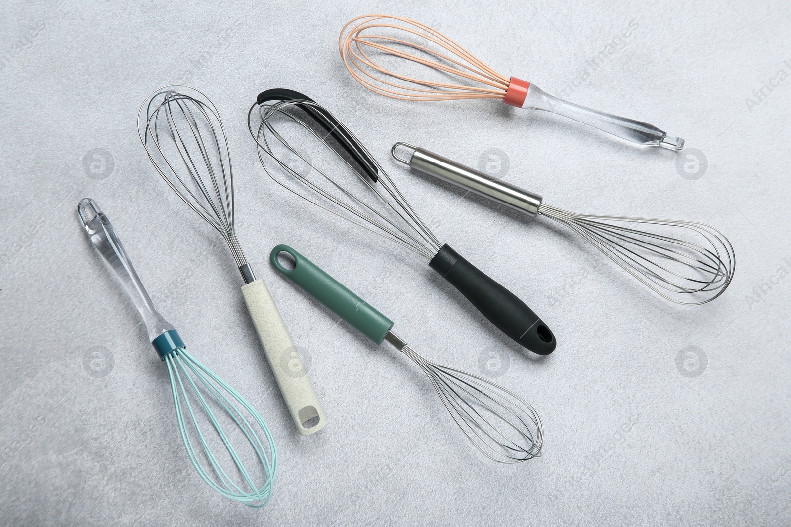 Photo of Different whisks on gray table, flat lay