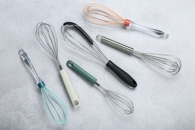 Photo of Different whisks on gray table, flat lay