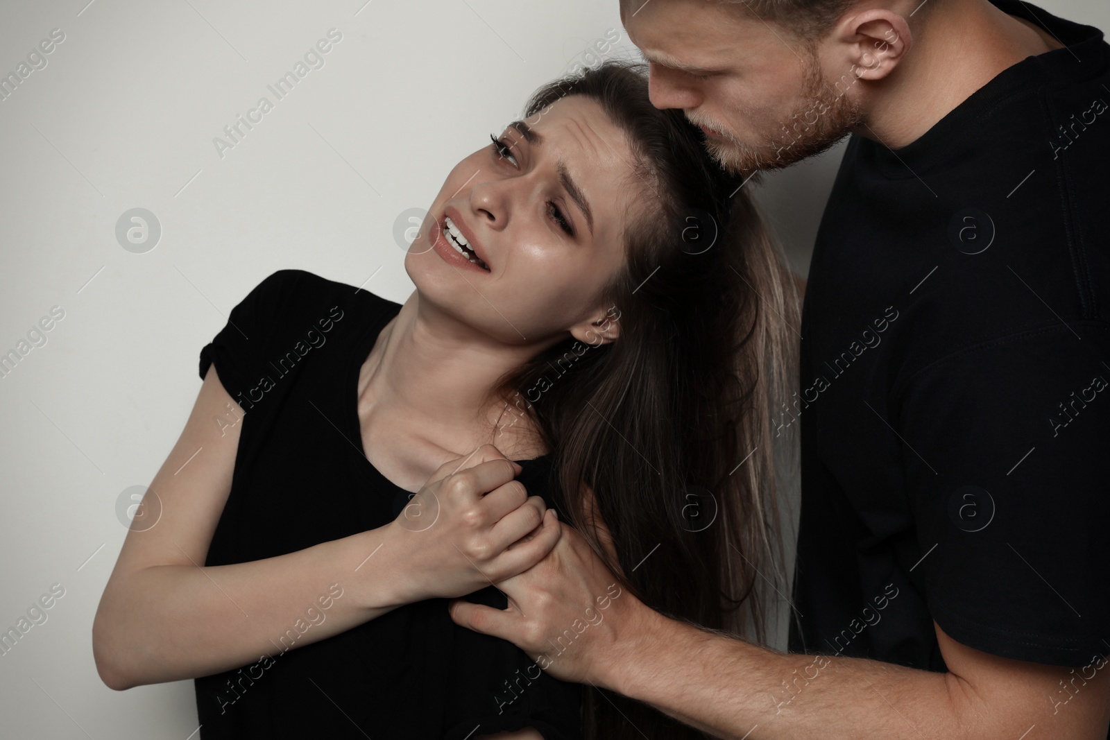 Photo of Man fighting with woman on light background. Stop sexual assault