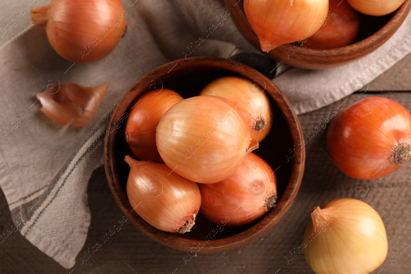 Photo of Many ripe onions on wooden table, flat lay