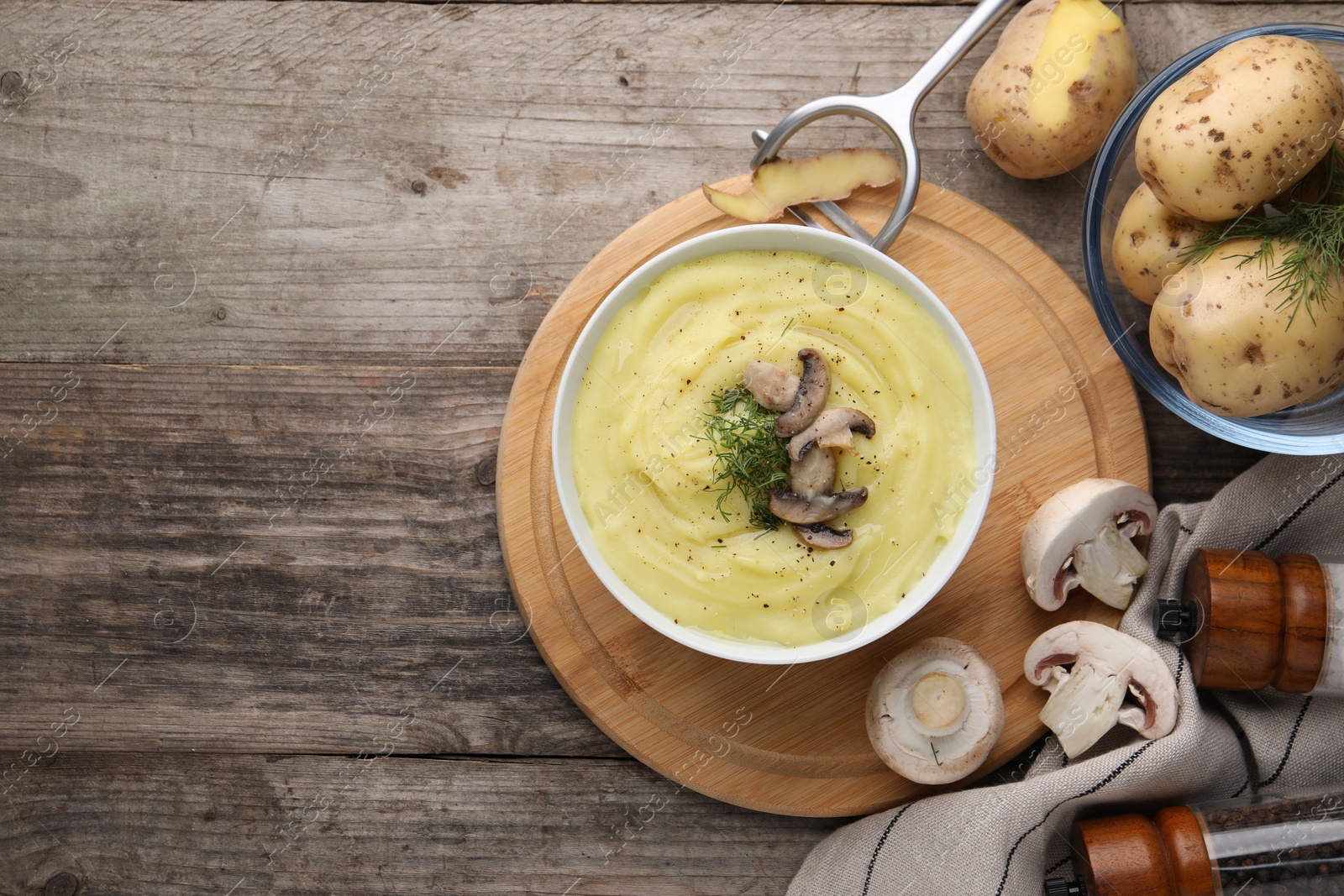 Photo of Bowl of tasty cream soup with mushrooms, dill and raw potatoes on wooden table, flat lay. Space for text
