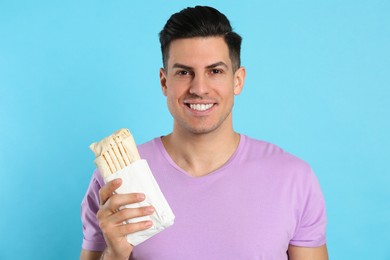 Man with delicious shawarma on turquoise background