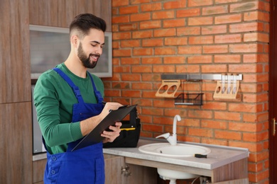 Male plumber with clipboard near kitchen sink. Repair service