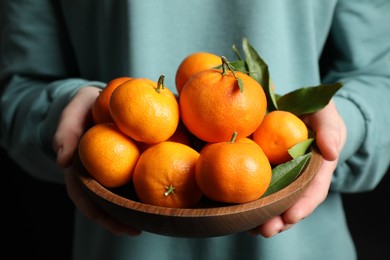 Woman holding bowl of tangerines, closeup. Juicy citrus fruit