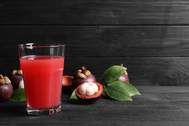 Delicious fresh mangosteen juice on black wooden table. Space for text