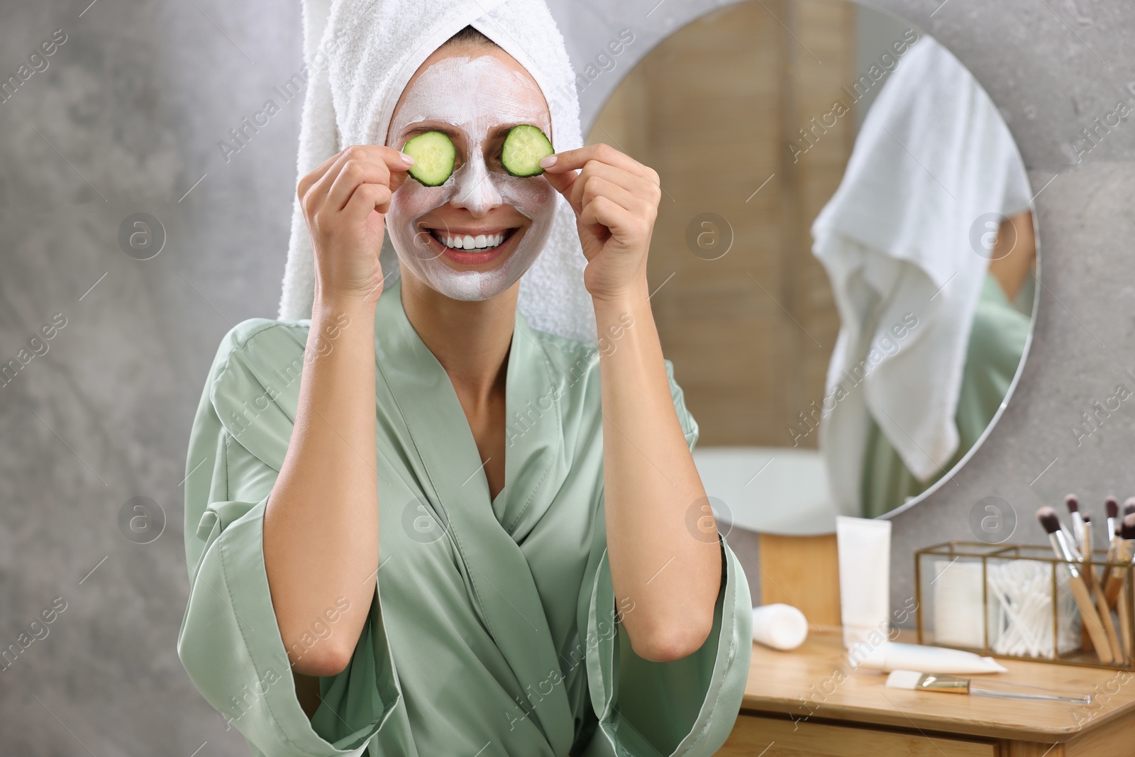 Photo of Woman with face mask and cucumber slices in bathroom, space for text. Spa treatments