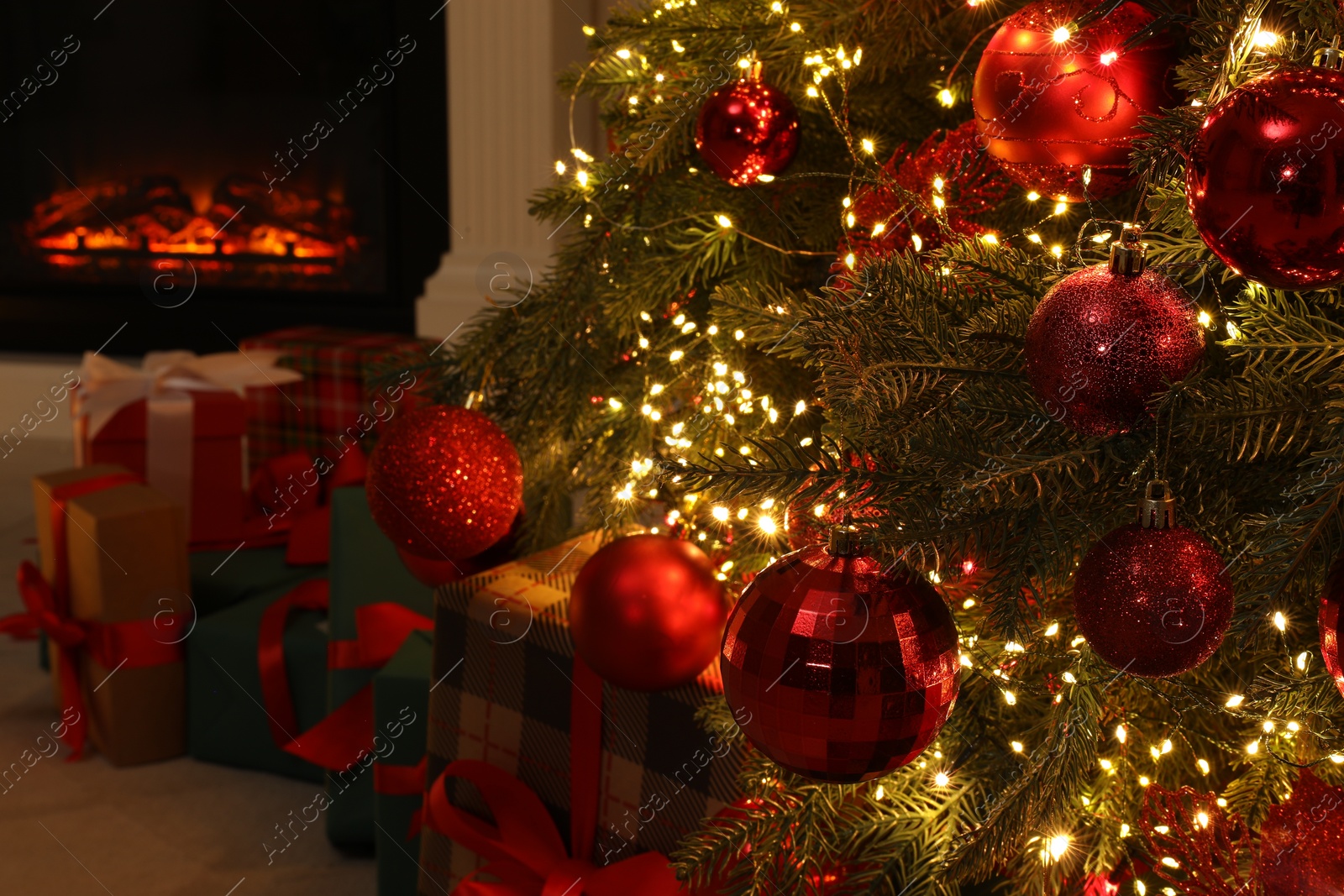 Photo of Many gift boxes under decorated Christmas tree and fireplace indoors