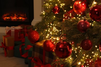 Many gift boxes under decorated Christmas tree and fireplace indoors