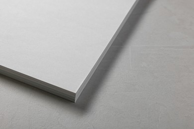 Blank paper sheets on grey textured table, closeup. Mockup for design