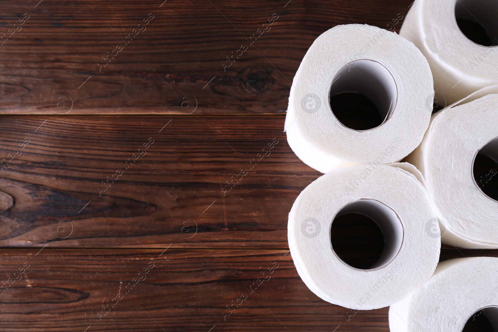 Photo of Many soft toilet paper rolls on wooden table, flat lay. Space for text