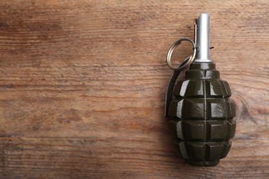 Photo of Hand grenade on wooden table, top view. Space for text