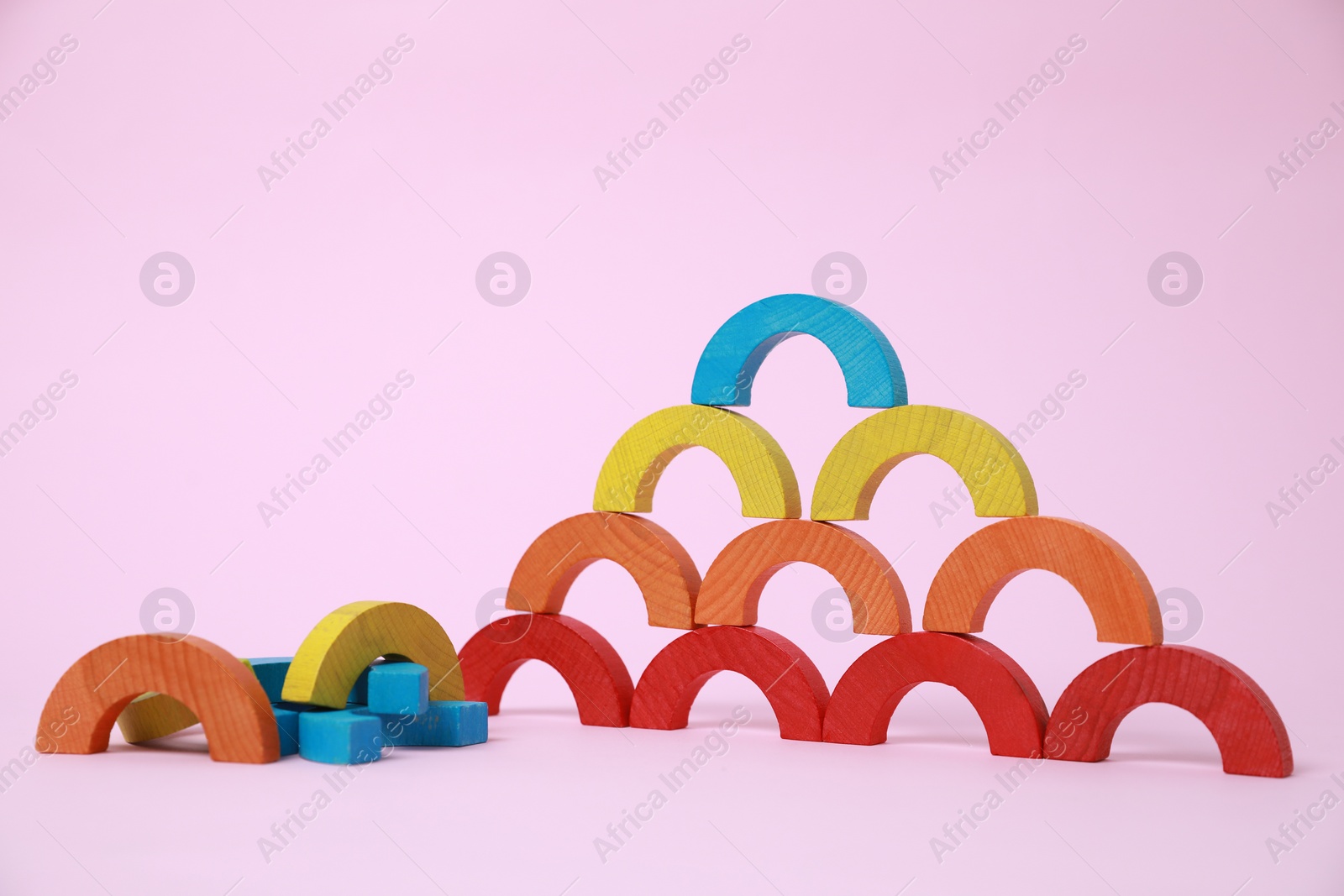 Photo of Colorful wooden pieces of playing set on pink background. Educational toy for motor skills development