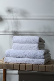 Photo of Stacked terry towels on wicker bench indoors, space for text