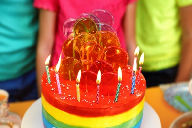 Photo of Children near cake with candles at birthday party indoors, closeup