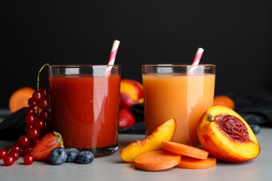 Delicious juices and fresh ingredients on grey table against black background