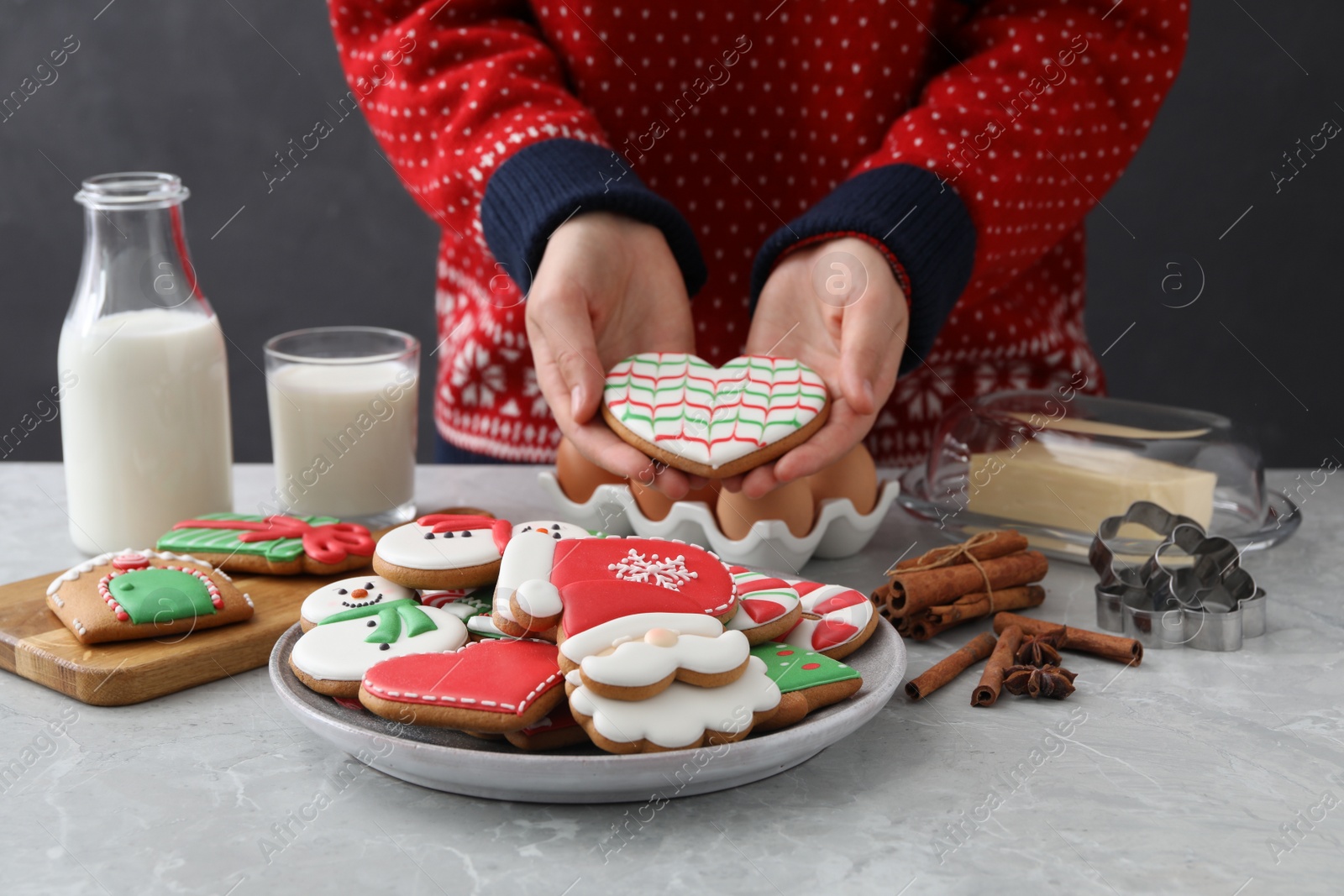 Photo of Woman holding delicious homemade Christmas cookie at grey marble table, closeup