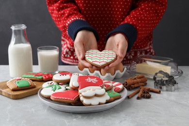 Woman holding delicious homemade Christmas cookie at grey marble table, closeup