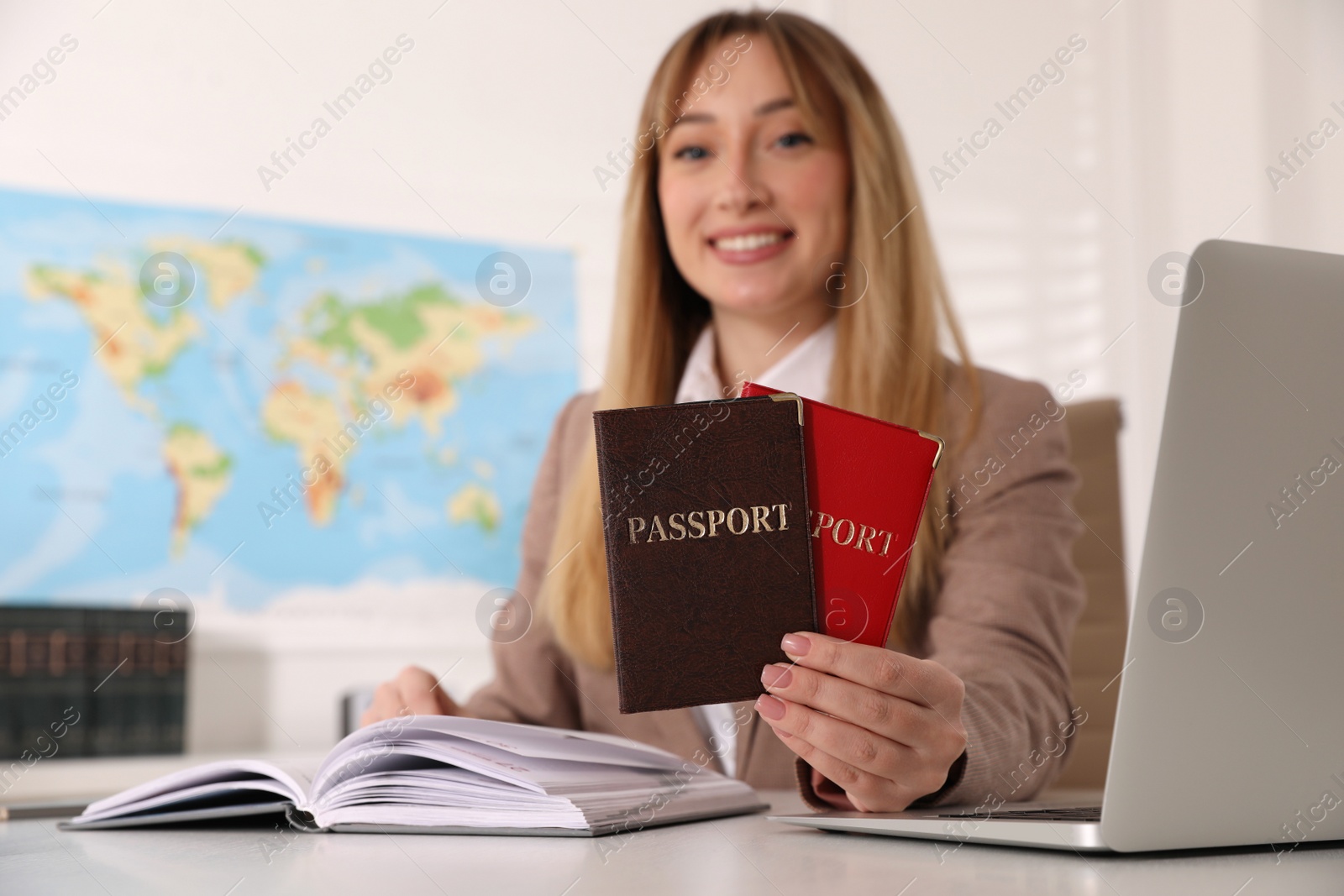 Photo of Happy manager holding passports at desk in travel agency, focus on documents