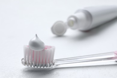 Photo of Brush with toothpaste and tube on white background, closeup