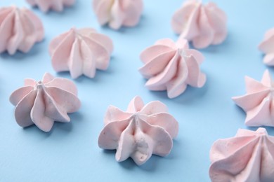 Photo of Tasty meringue cookies on light blue background, closeup