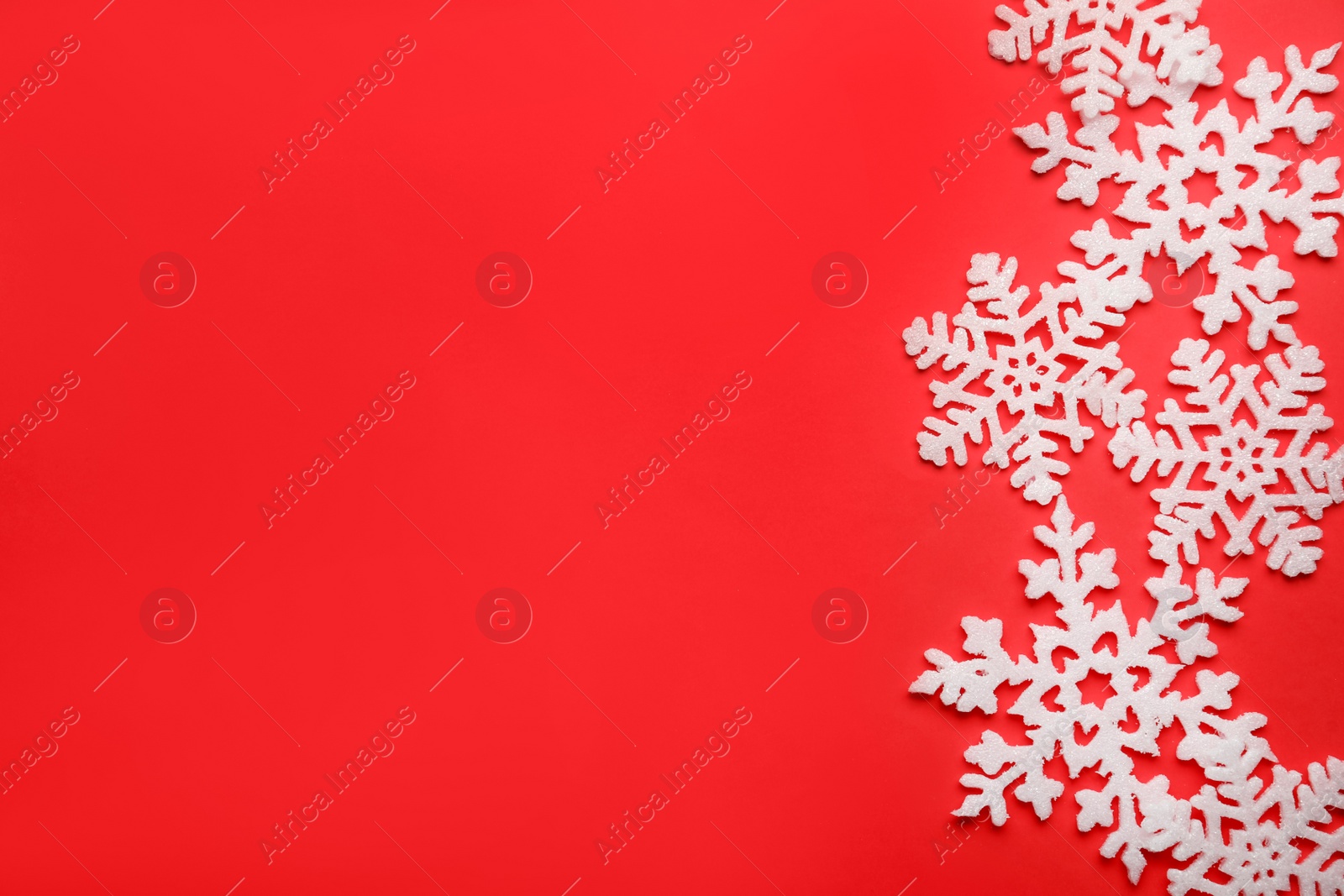 Photo of Beautiful decorative snowflakes on red background, flat lay. Space for text