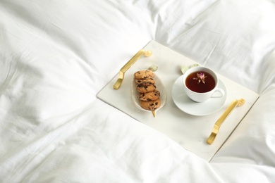 Photo of Cup of aromatic tea and cookies on soft blanket. Space for text