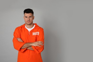Photo of Prisoner in orange jumpsuit on grey background, space for text