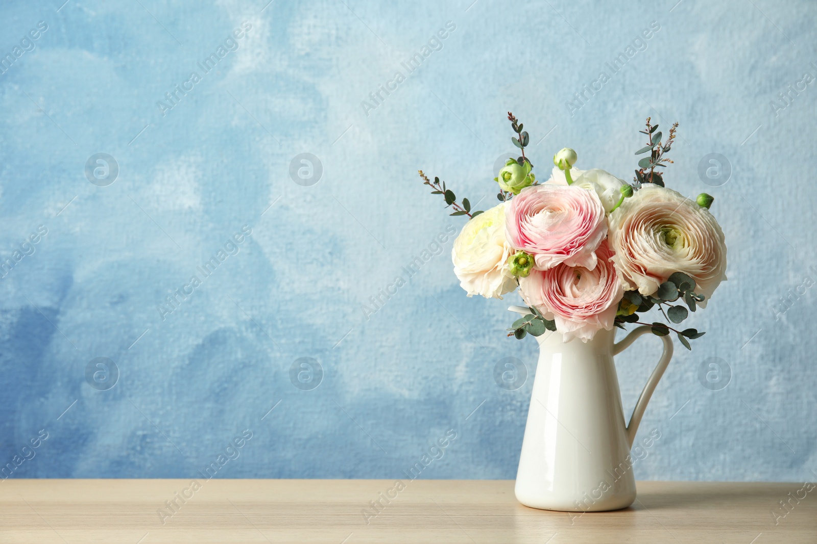 Photo of Vase with beautiful spring ranunculus flowers on table. Space for text