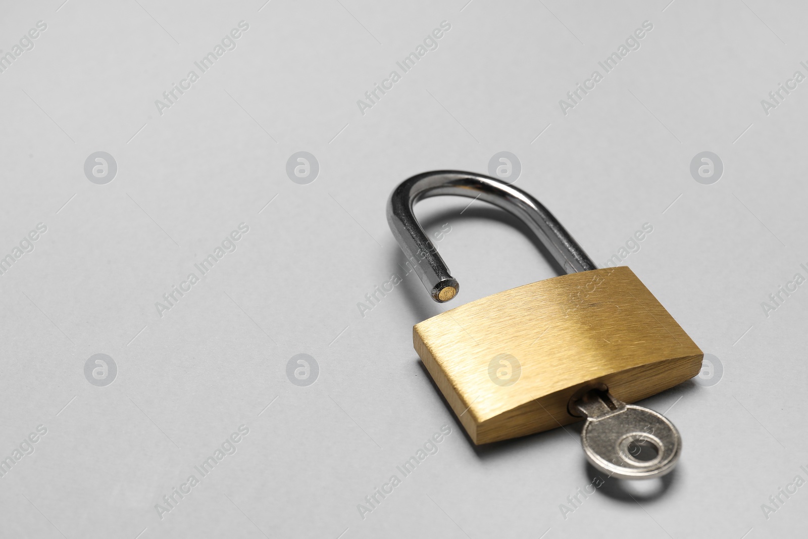 Photo of Steel padlock with key on grey background, closeup. Space for text