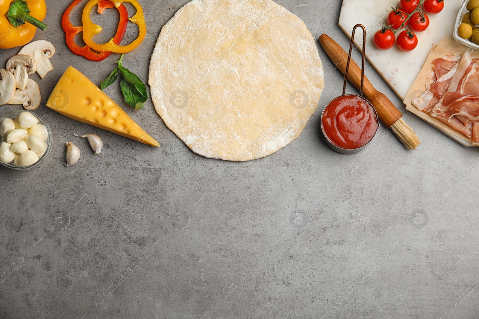 Photo of Flat lay composition with dough and fresh ingredients on grey table, space for text. Pizza recipe