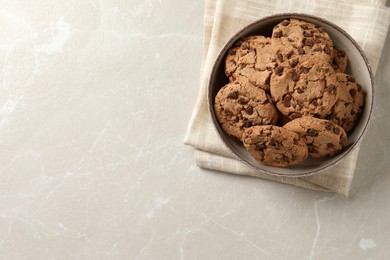 Photo of Delicious chocolate chip cookies in bowl on light grey table, top view. Space for text
