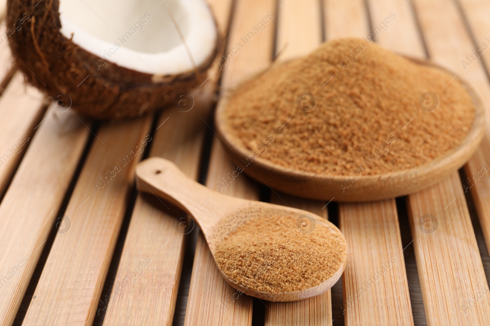 Photo of Coconut sugar, spoon, plate and fruit on wooden table, closeup