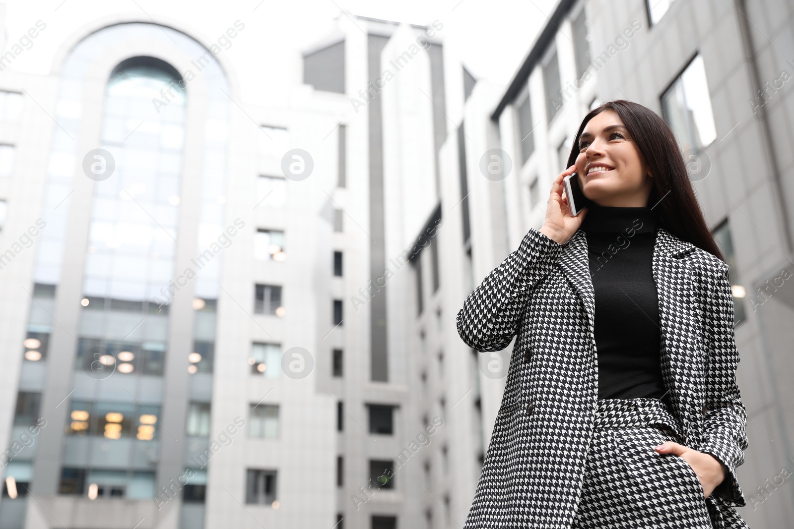 Photo of Beautiful woman in stylish suit talking on phone outdoors. Space for text