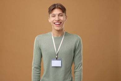 Happy man with blank badge on light brown background