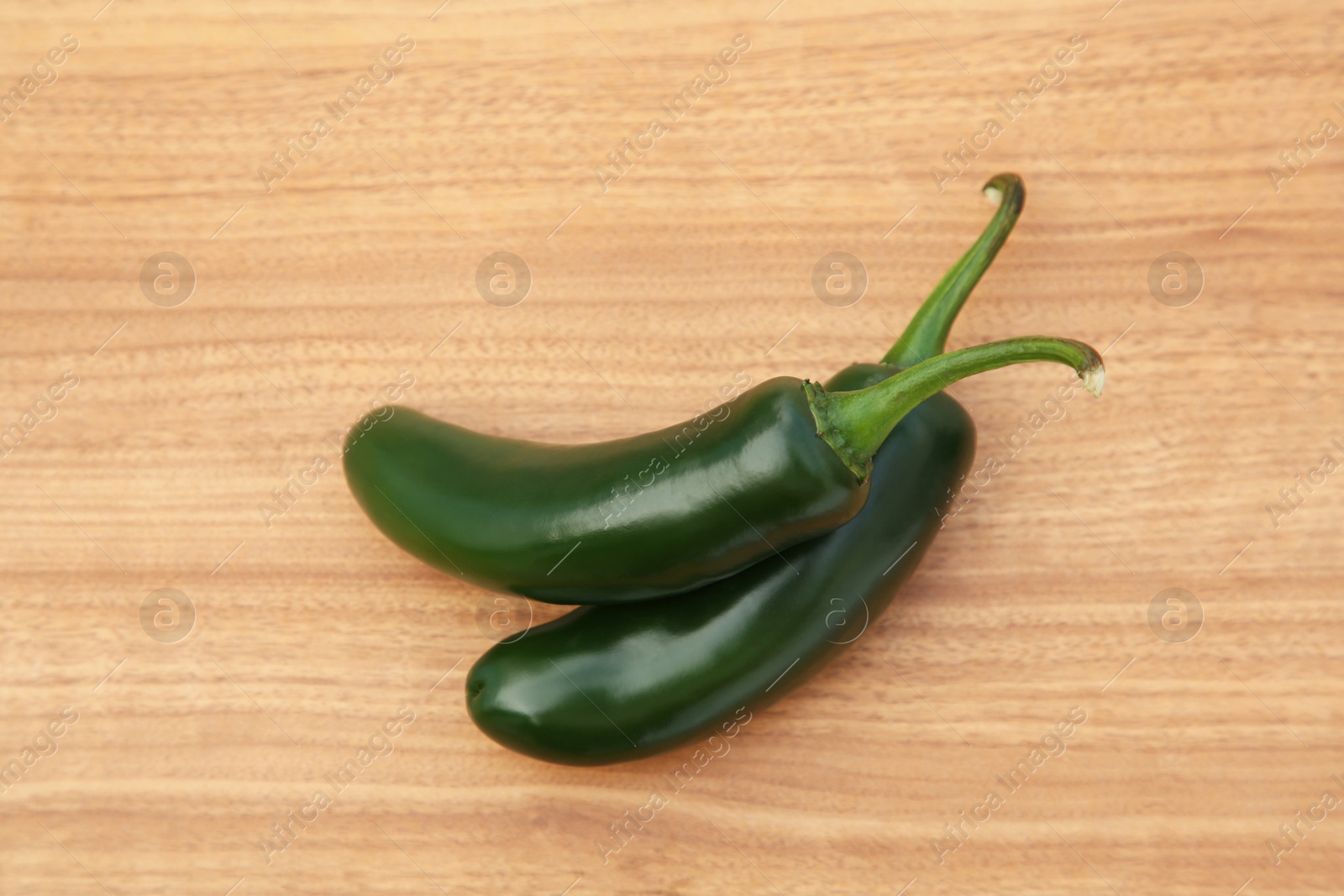 Photo of Fresh green jalapeno peppers on wooden table, top view