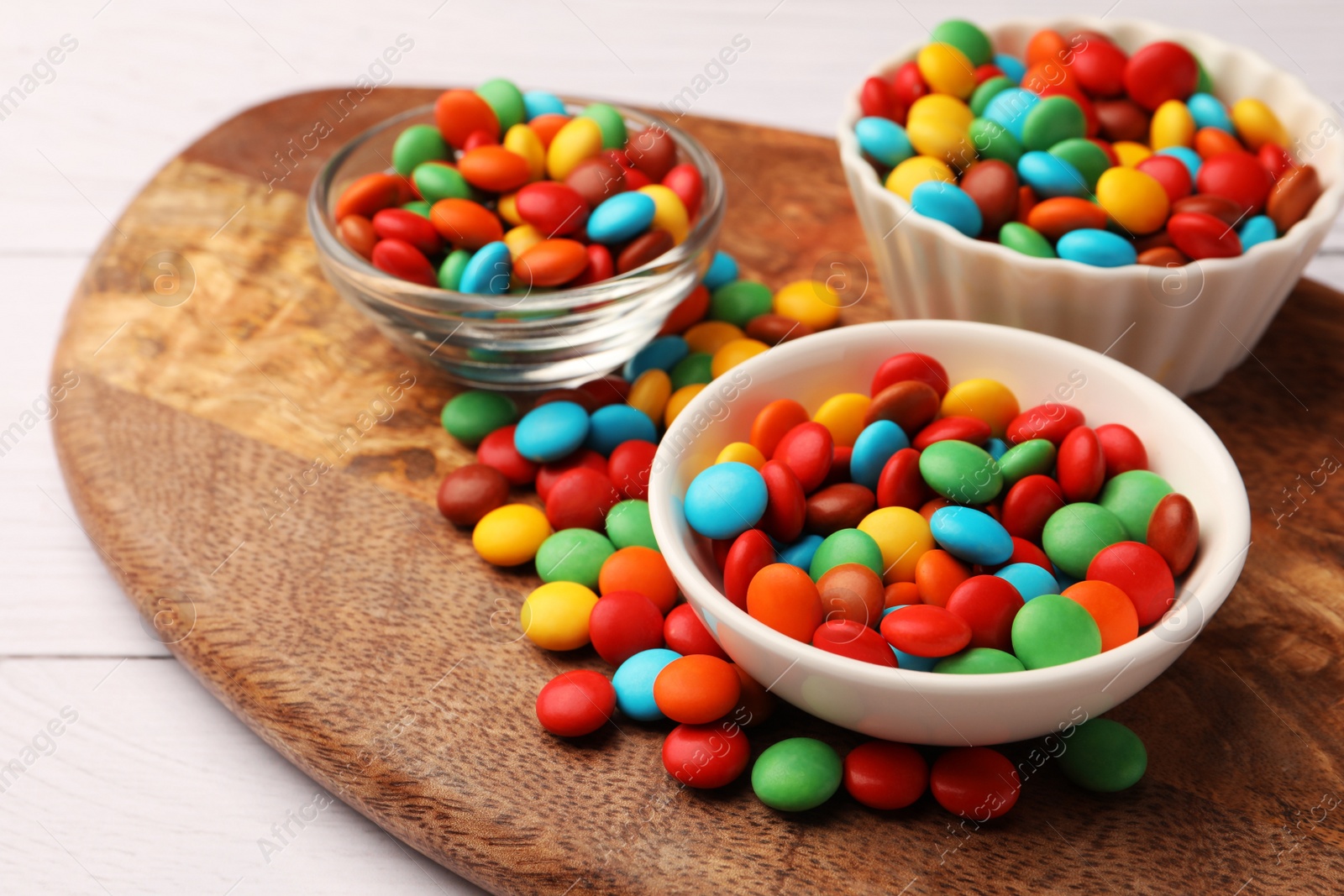 Photo of Tasty colorful candies on white wooden table, closeup